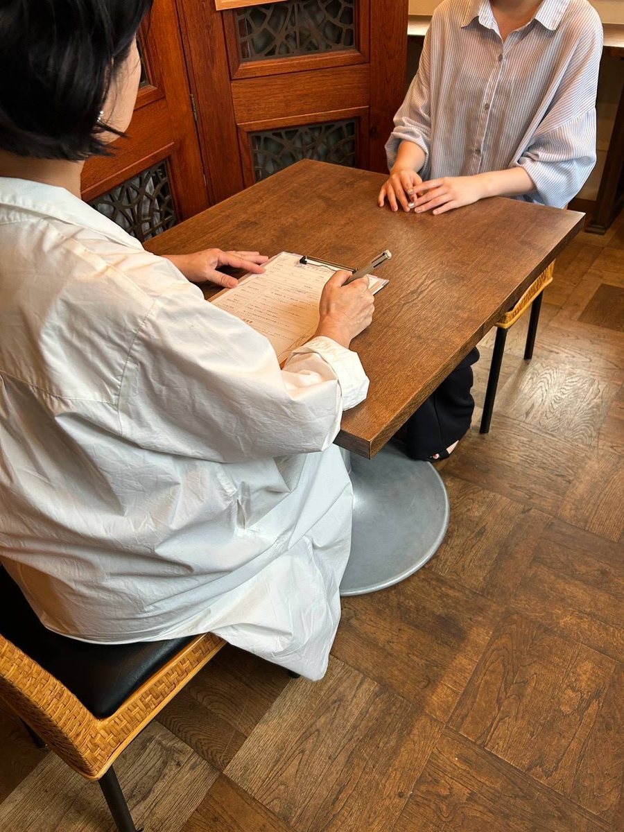 テーブルをはさんで、施術前にお話をうかがっている様子